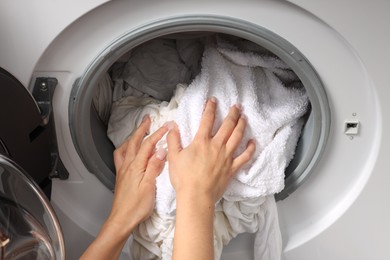 Photo of Woman taking clean clothes out of washing machine, closeup