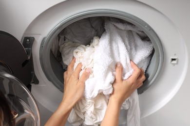 Woman taking clean clothes out of washing machine, closeup