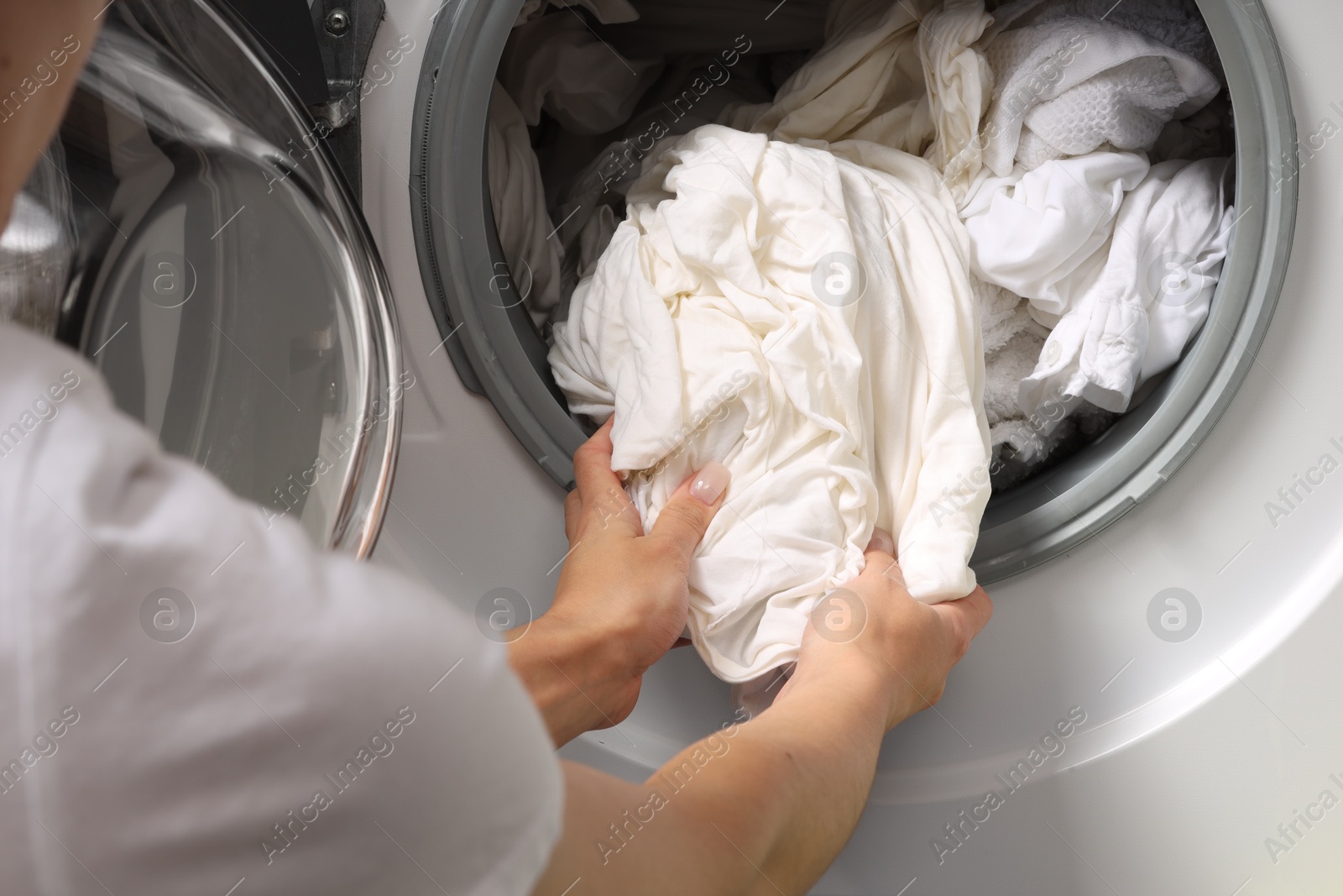 Photo of Woman taking clean clothes out of washing machine, closeup