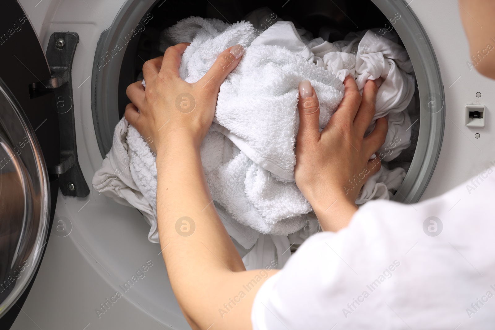 Photo of Woman taking clean clothes out of washing machine, closeup