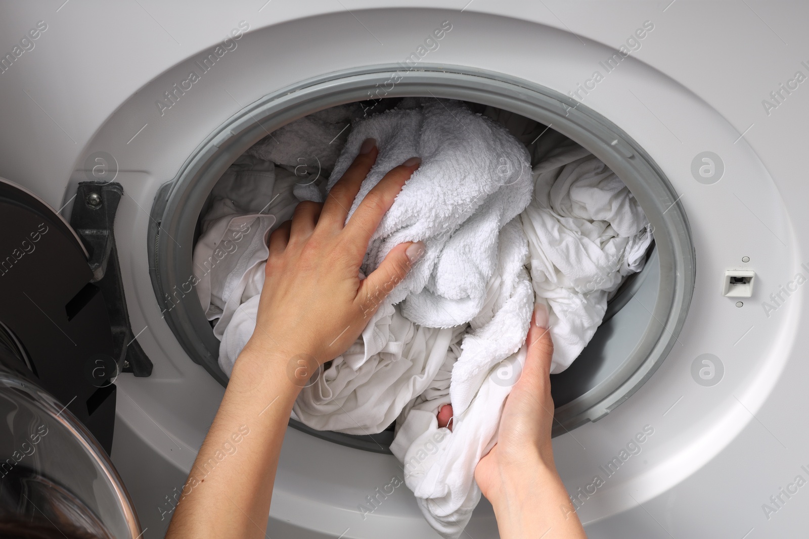 Photo of Woman taking clean clothes out of washing machine, closeup