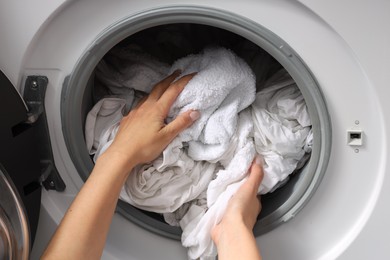 Woman taking clean clothes out of washing machine, closeup