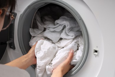 Photo of Woman taking clean clothes out of washing machine, closeup