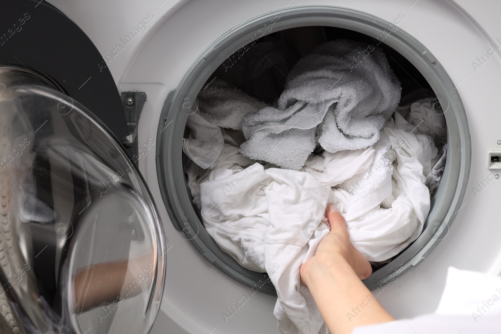 Photo of Woman taking clean clothes out of washing machine, closeup