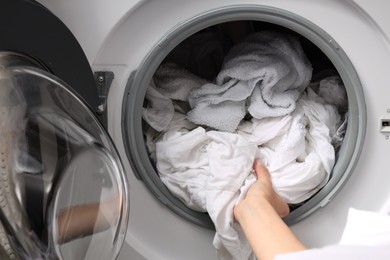 Woman taking clean clothes out of washing machine, closeup