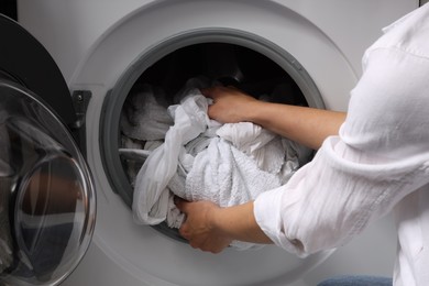 Woman taking clean clothes out of washing machine, closeup