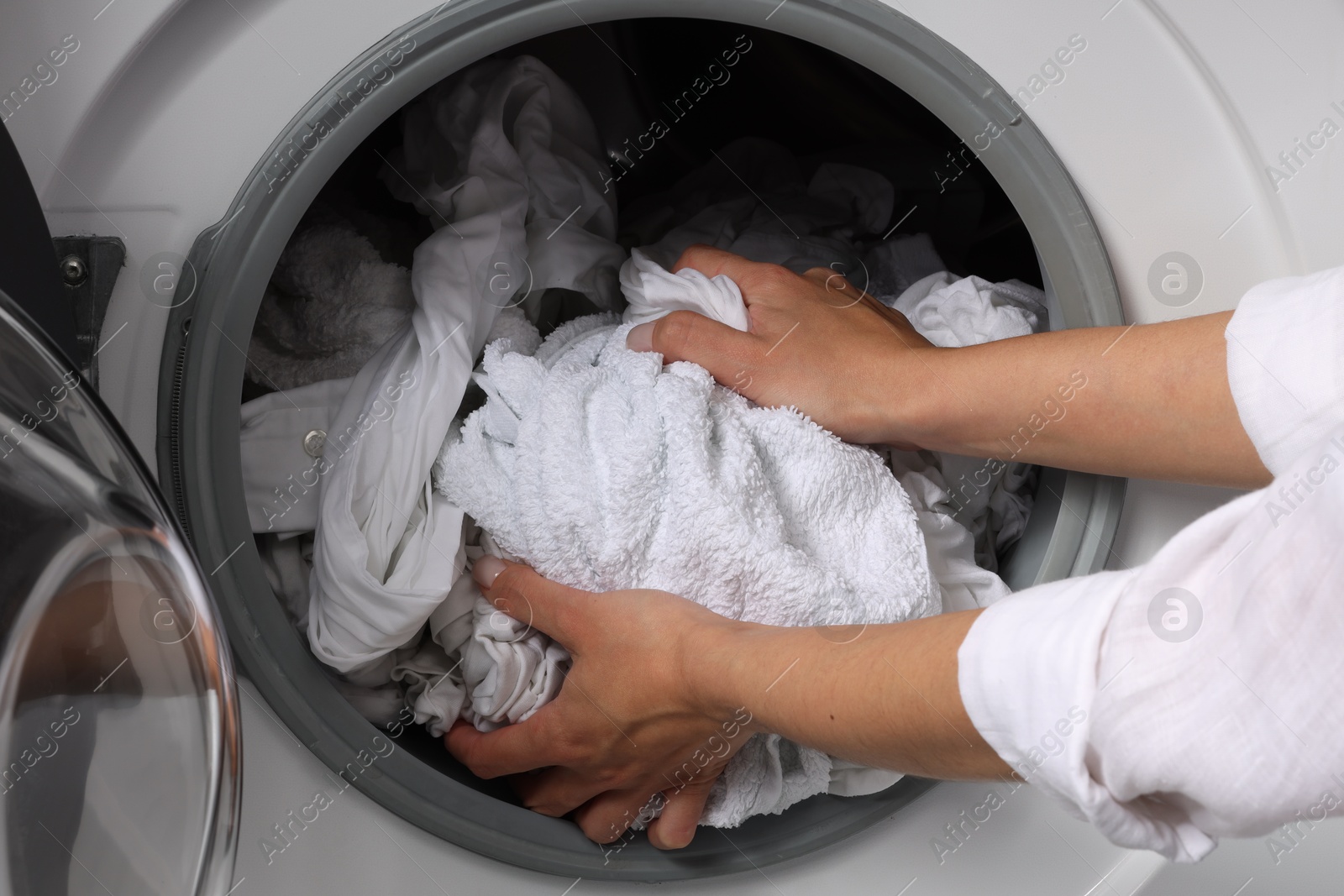 Photo of Woman taking clean clothes out of washing machine, closeup