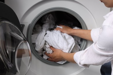 Woman taking clean clothes out of washing machine, closeup