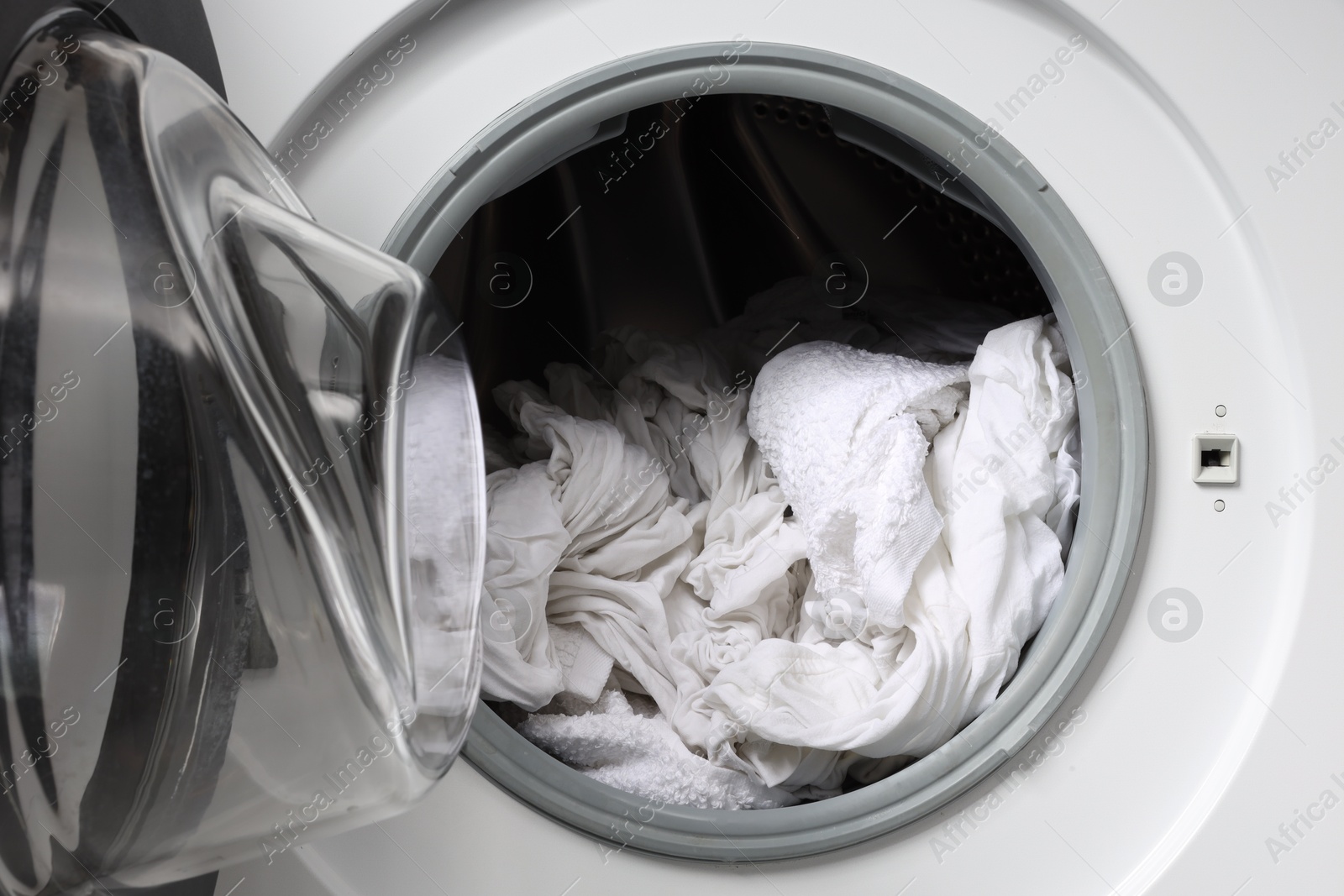 Photo of Open washing machine with clean clothes, closeup