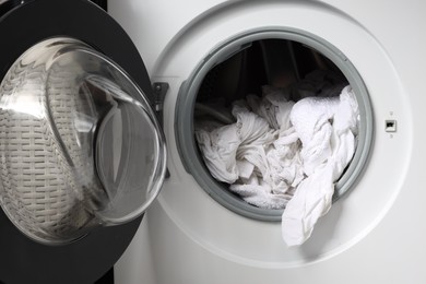 Photo of Open washing machine with clean clothes, closeup