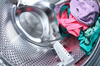 Washing machine with laundry as background, closeup