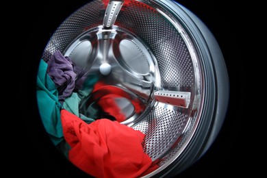 Photo of Washing machine with laundry as background, closeup