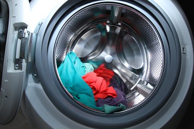 Washing machine with laundry as background, closeup