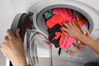 Woman putting dirty laundry into washing machine, closeup