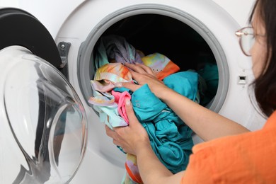 Woman putting dirty laundry into washing machine, closeup