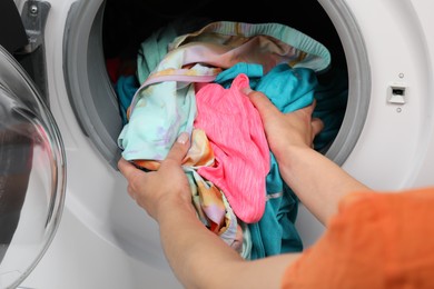 Woman putting dirty laundry into washing machine, closeup