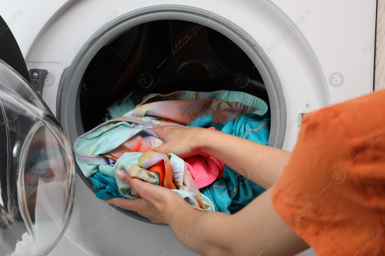 Photo of Woman putting dirty laundry into washing machine, closeup