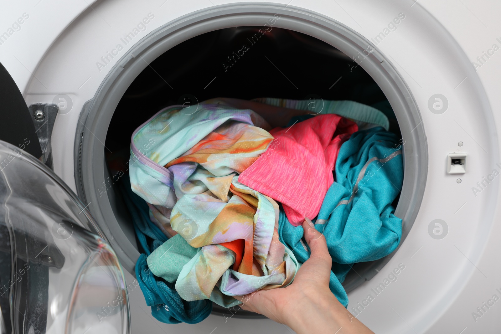 Photo of Woman putting dirty laundry into washing machine, closeup