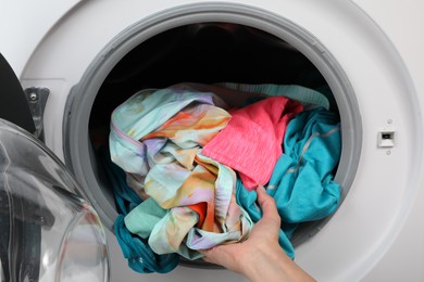 Woman putting dirty laundry into washing machine, closeup