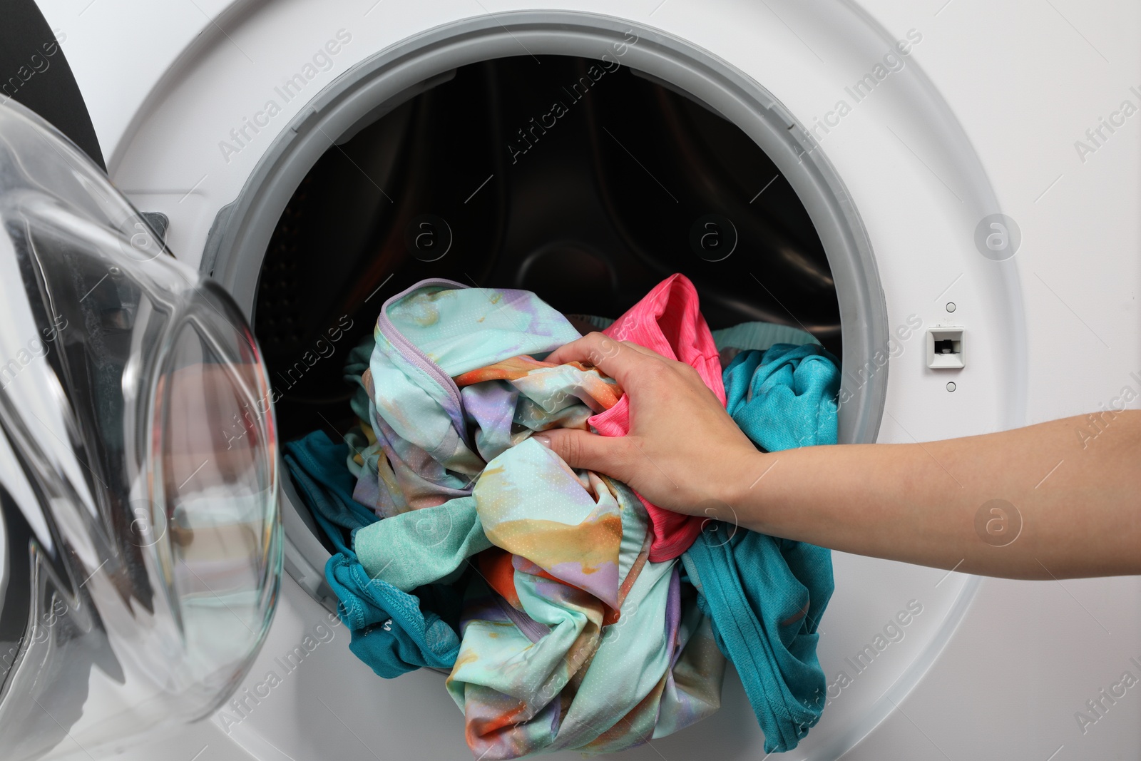 Photo of Woman putting dirty laundry into washing machine, closeup