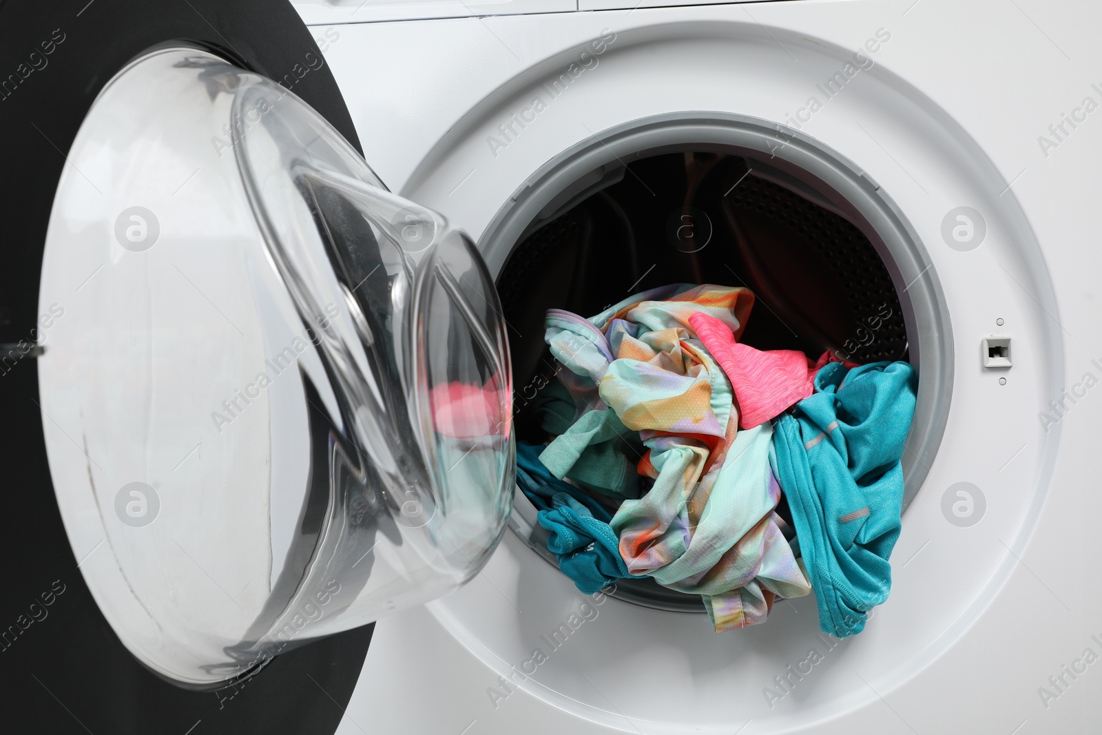 Photo of Washing machine with laundry as background, closeup