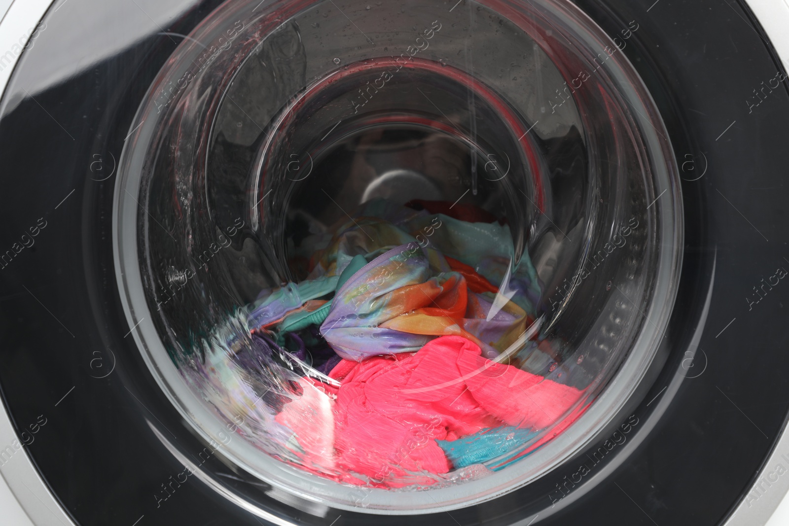 Photo of Washing machine with laundry as background, closeup