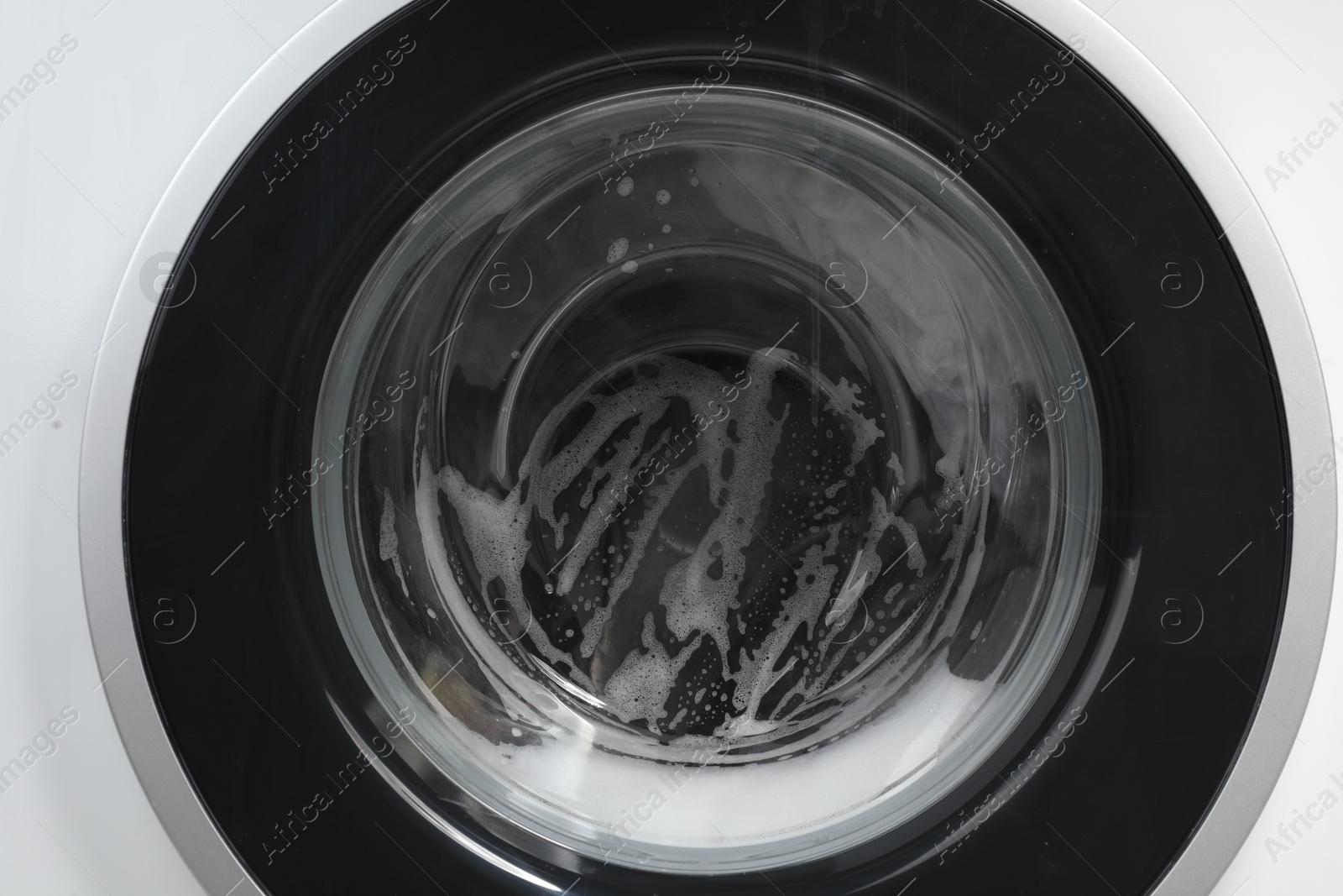 Photo of Washing machine with suds as background, closeup