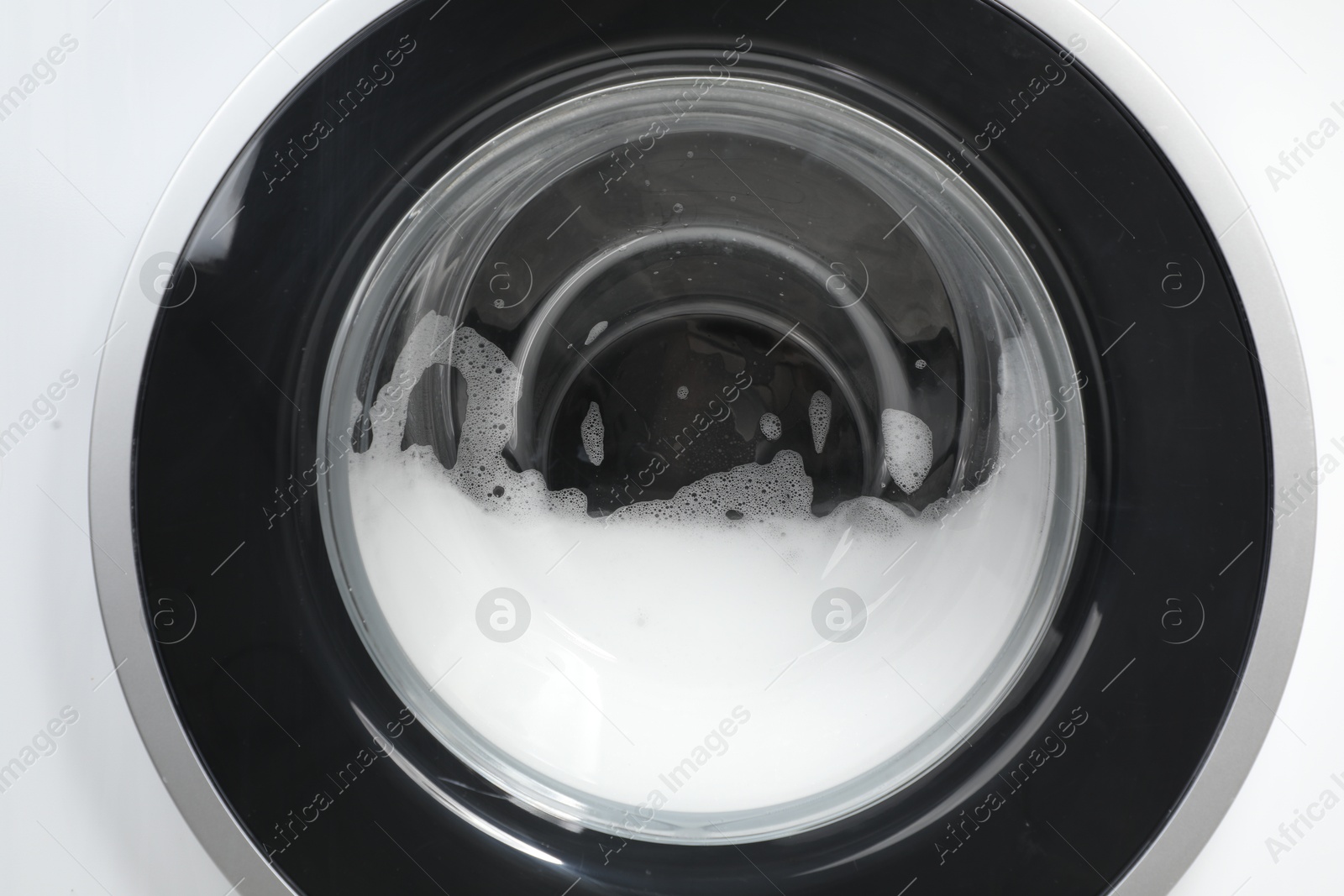 Photo of Washing machine with suds as background, closeup