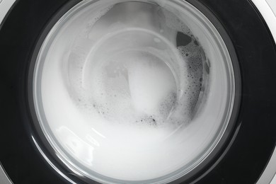 Photo of Washing machine with suds as background, closeup