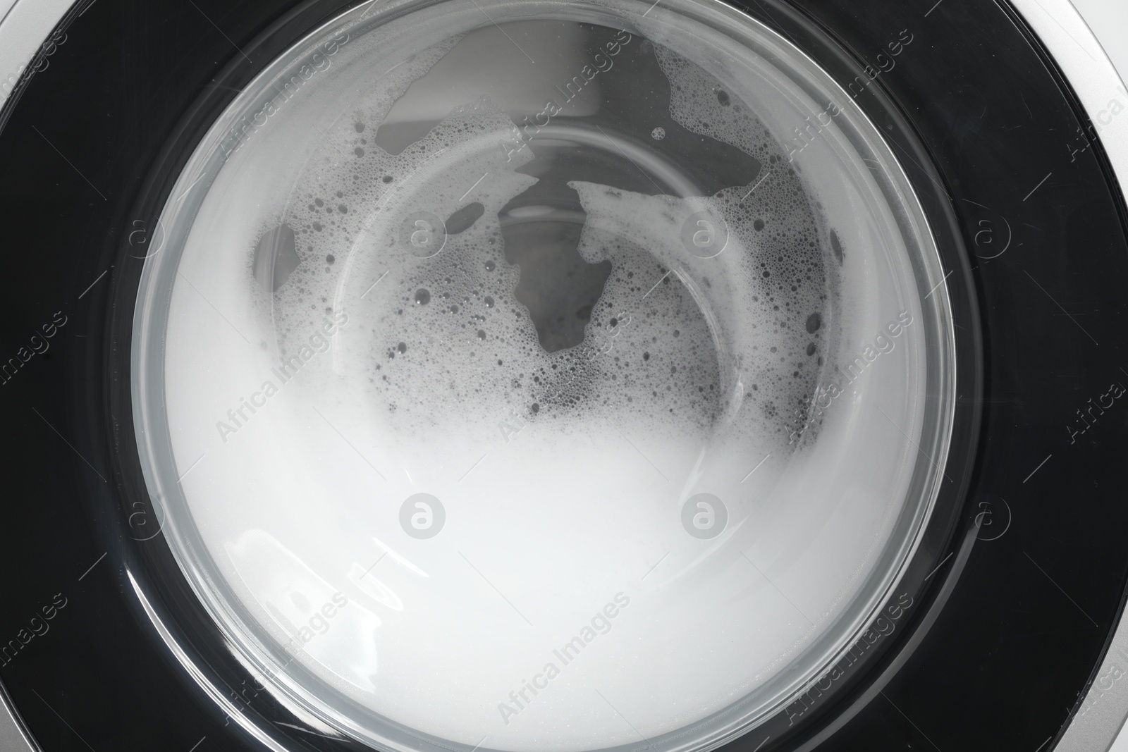 Photo of Washing machine with suds as background, closeup