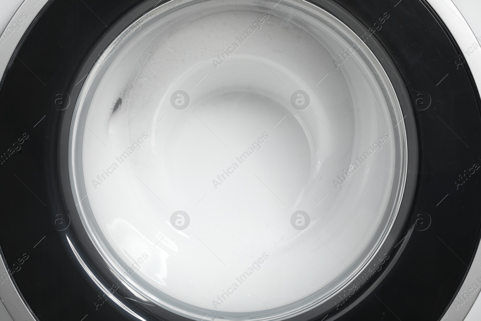 Photo of Washing machine with suds as background, closeup