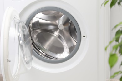 Washing machine with empty drum indoors, closeup