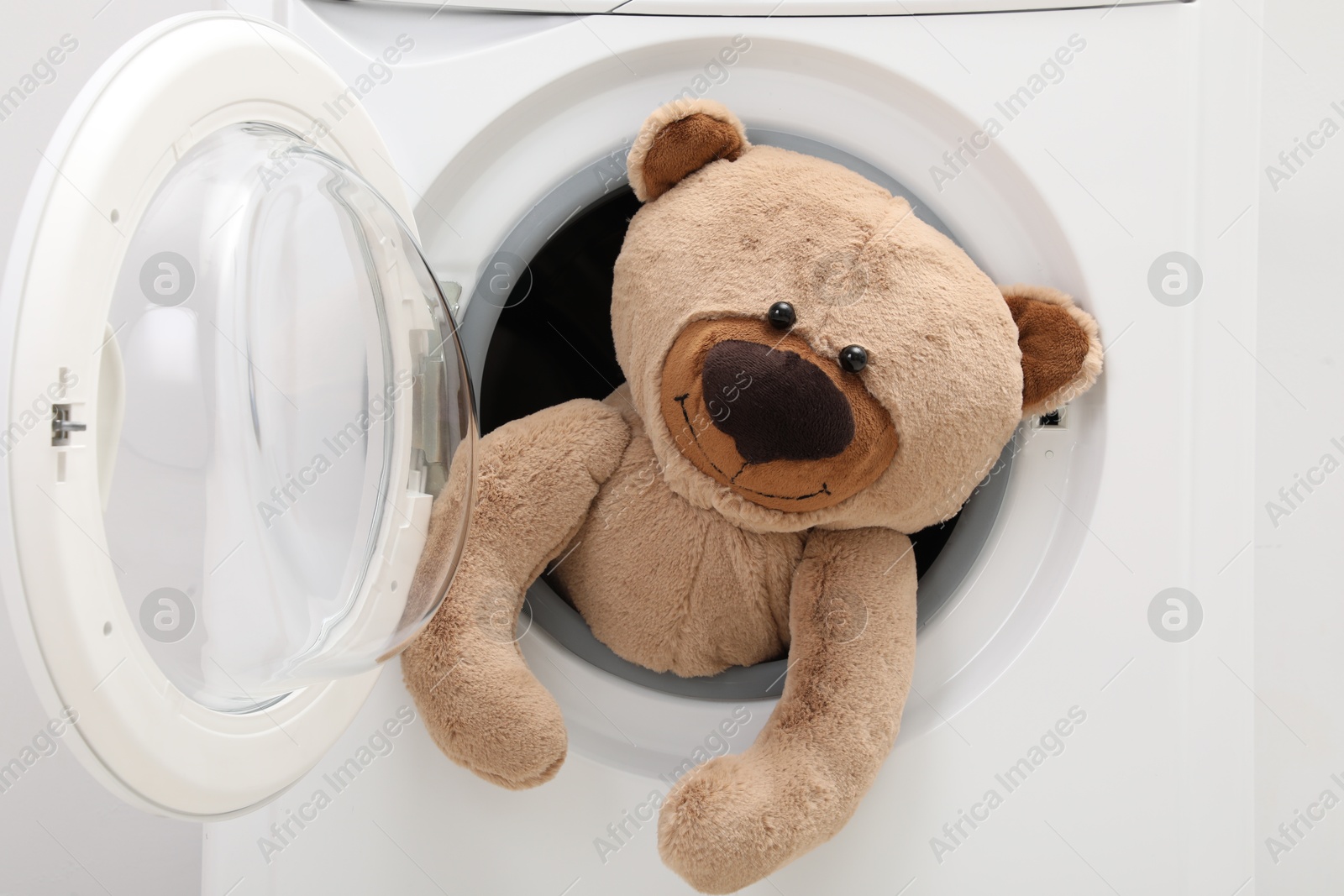 Photo of Washing machine with teddy bear as background, closeup