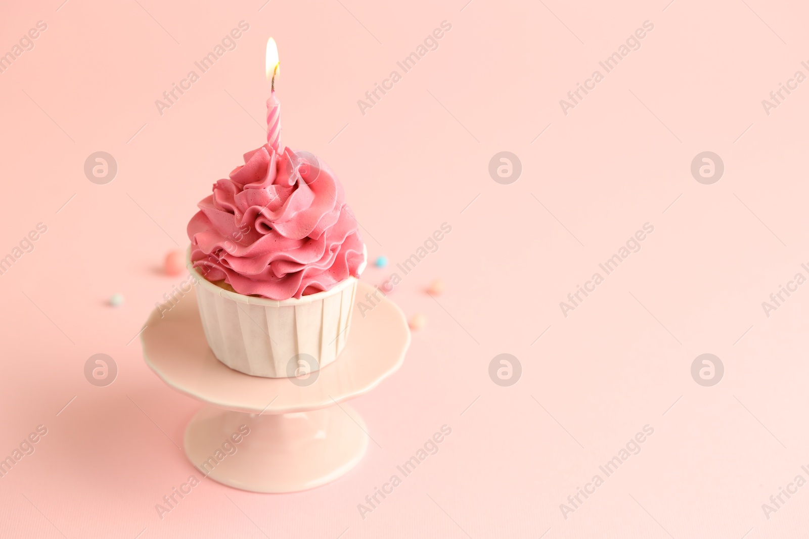 Photo of Tasty cupcake with burning candle on pink background, space for text