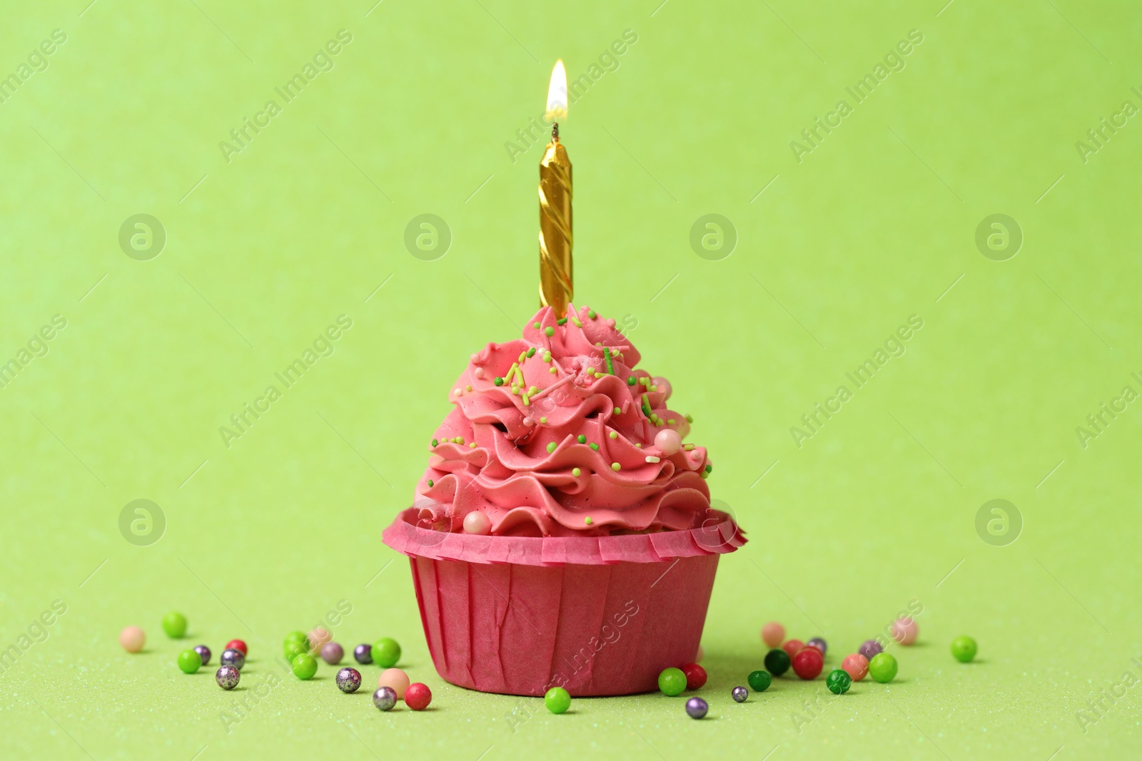 Photo of Tasty cupcake with burning candle on light green background