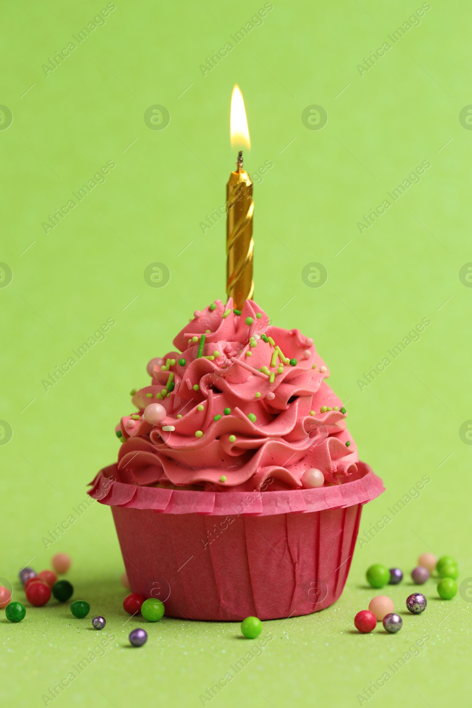 Photo of Tasty cupcake with burning candle on light green background