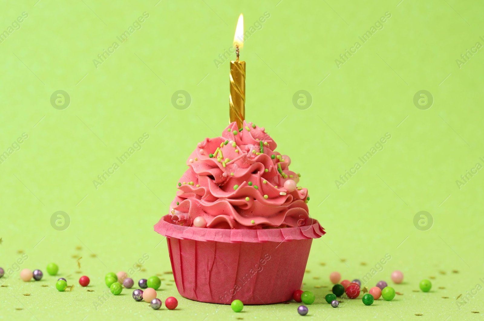 Photo of Tasty cupcake with burning candle on light green background