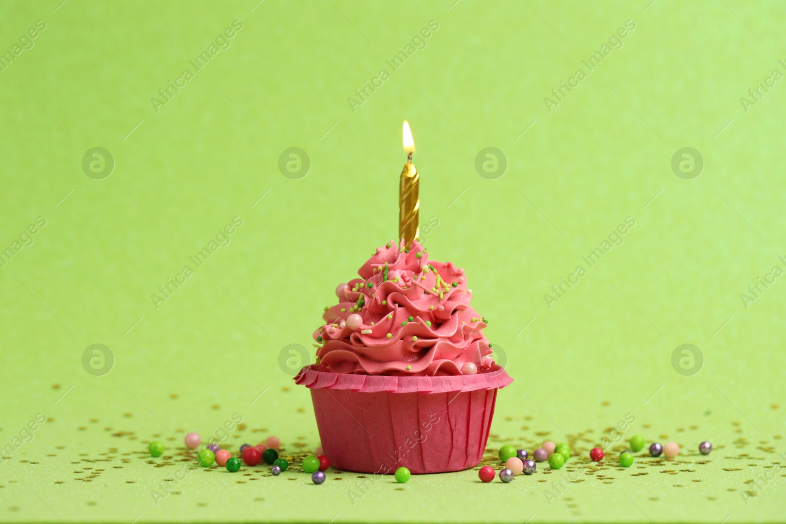 Photo of Tasty cupcake with burning candle on light green background