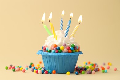 Photo of Tasty cupcake with burning candles on beige background