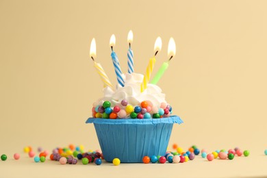 Photo of Tasty cupcake with burning candles on beige background