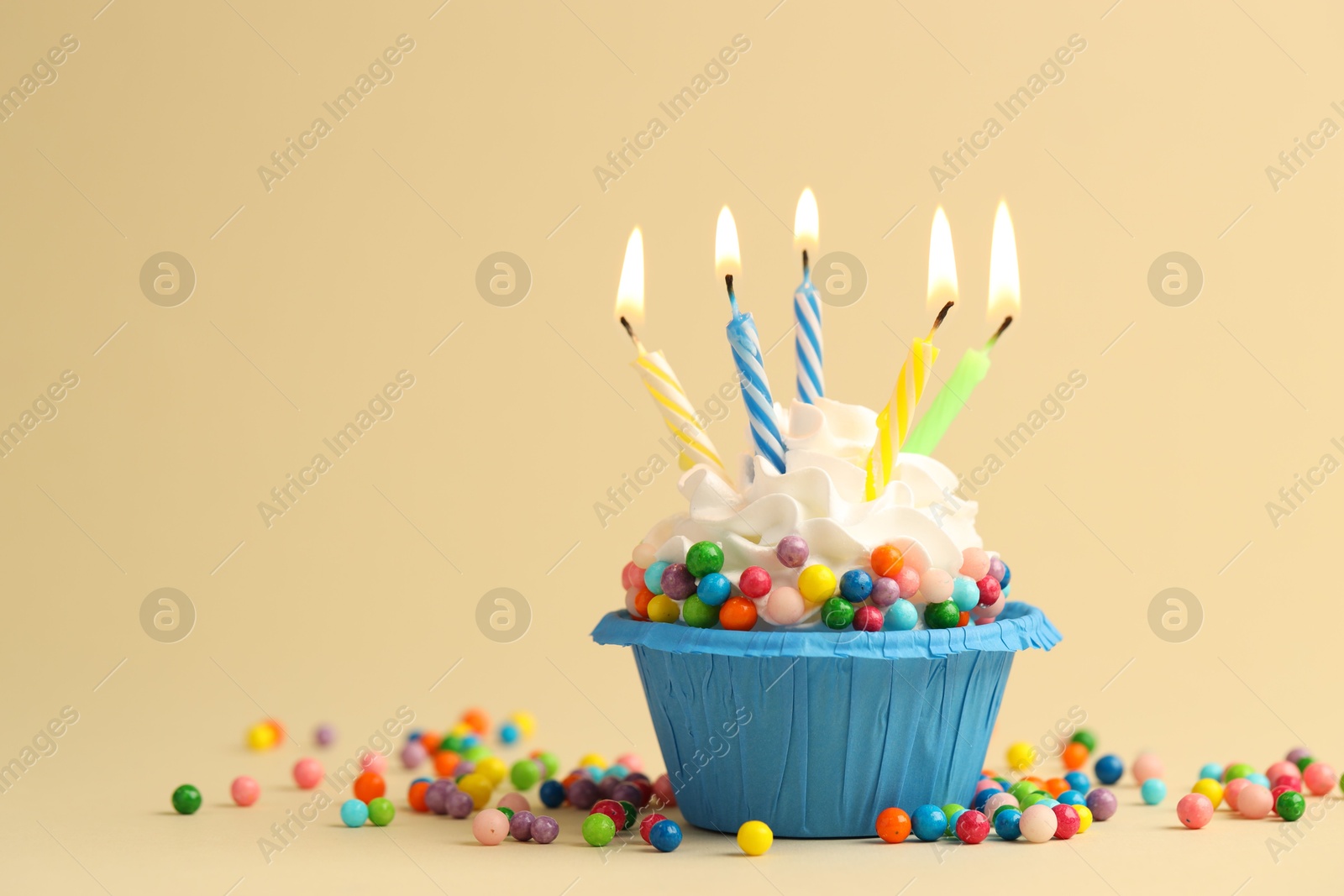 Photo of Tasty cupcake with burning candles on beige background