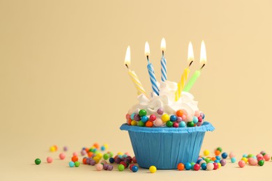 Photo of Tasty cupcake with burning candles on beige background