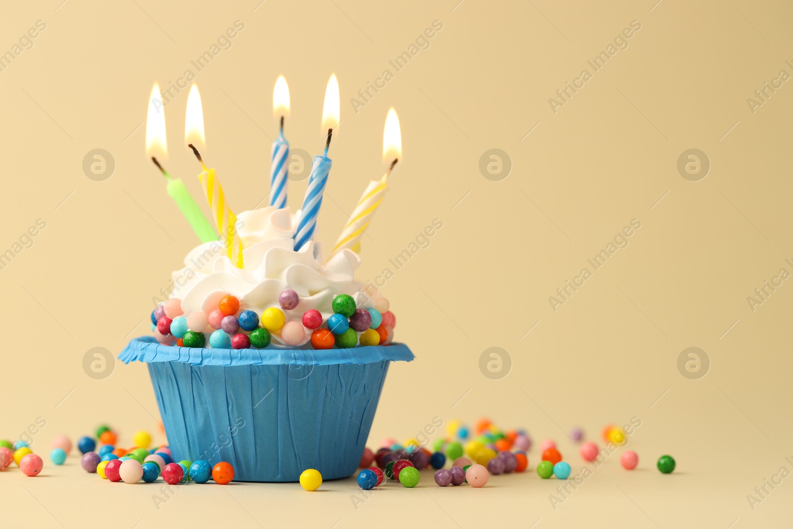 Photo of Tasty cupcake with burning candles on beige background