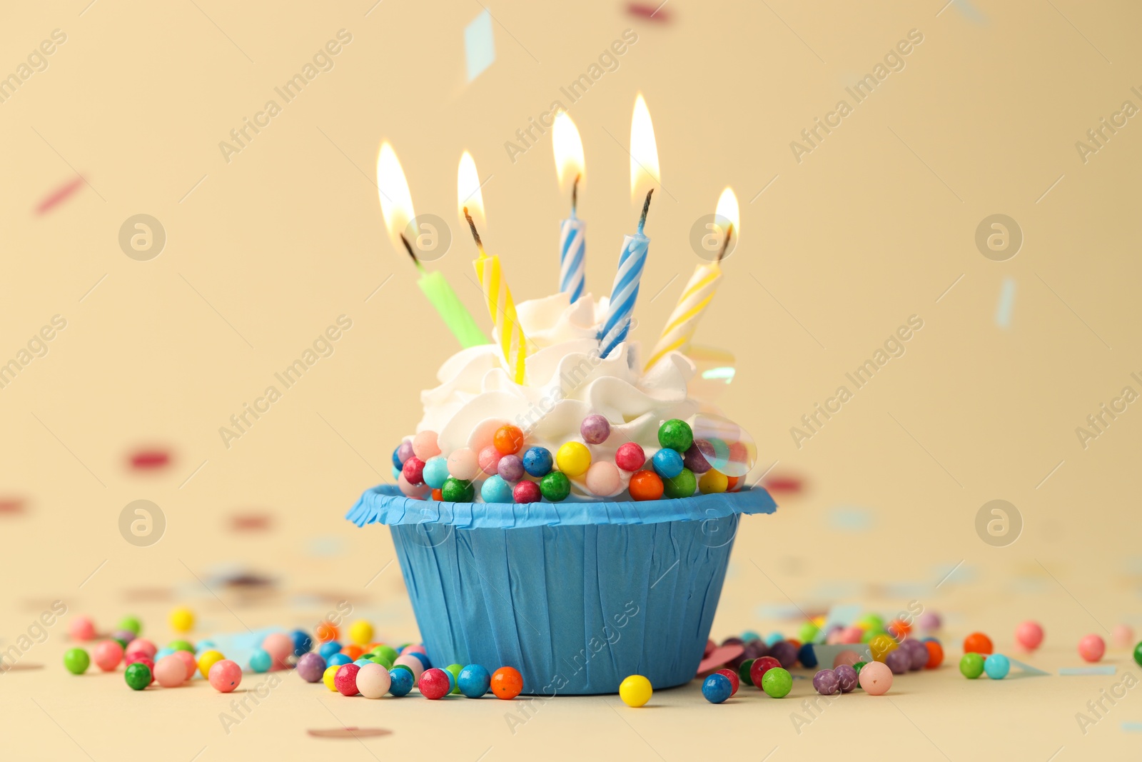 Photo of Tasty cupcake with burning candles on beige background