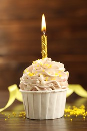 Photo of Tasty cupcake with burning candle on wooden table