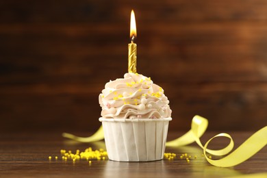 Photo of Tasty cupcake with burning candle on wooden table