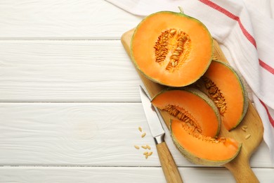 Photo of Cut ripe Cantaloupe melon and knife on white wooden table, flat lay. Space for text