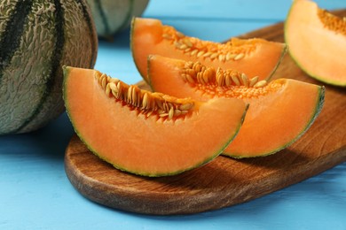 Photo of Tasty ripe Cantaloupe melon on light blue table, closeup