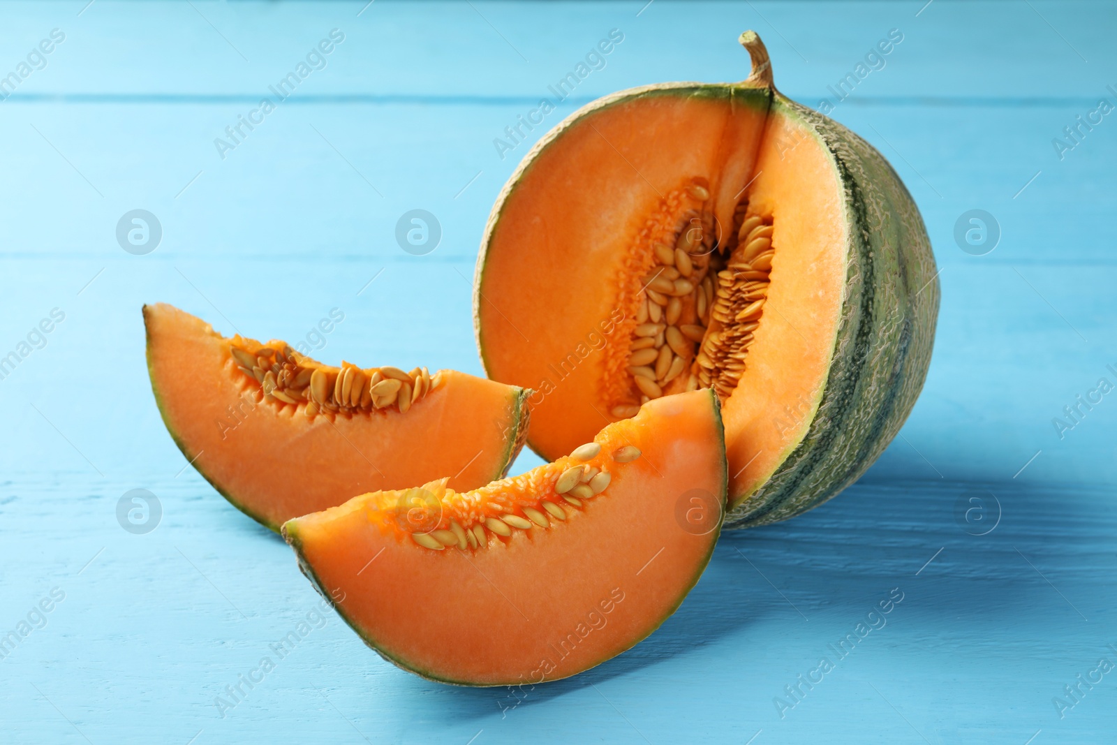 Photo of Cut ripe Cantaloupe melon on light blue wooden table, closeup