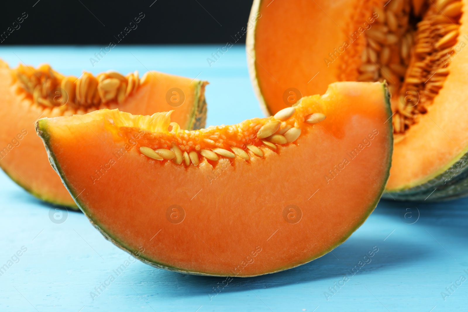 Photo of Cut ripe Cantaloupe melon on light blue wooden table, closeup